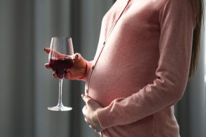 pregnant woman with a glass of wine indoors