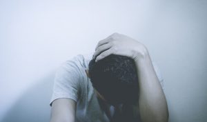 depressed man holding his head feeling sick
