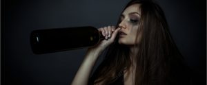 depressed woman drinking alcohol from a bottle