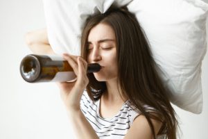 hungover woman drinking wine in bed