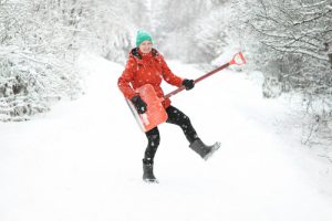 young woman having fun while removing snow